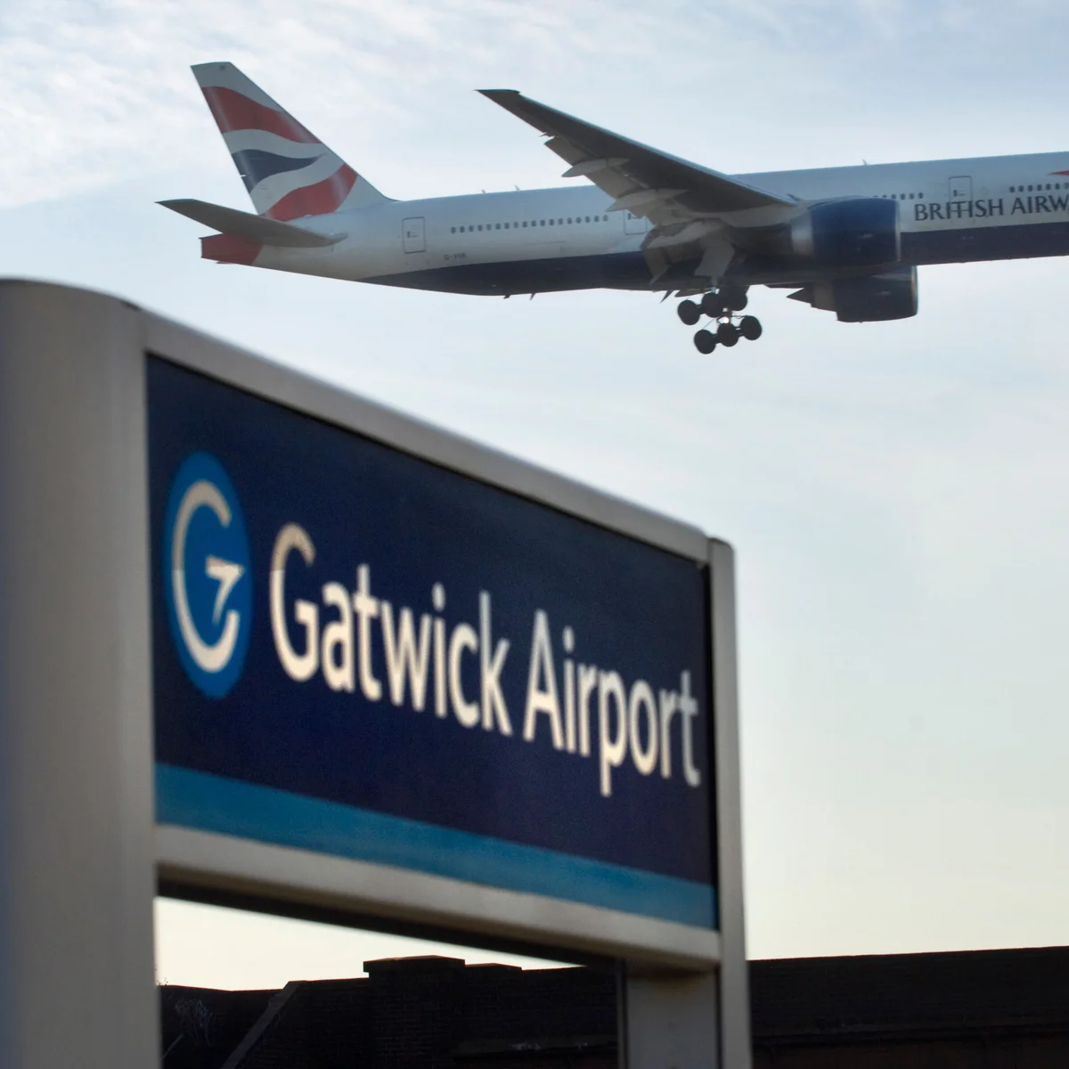 A jet on final approach above a Gatwick Airport sign